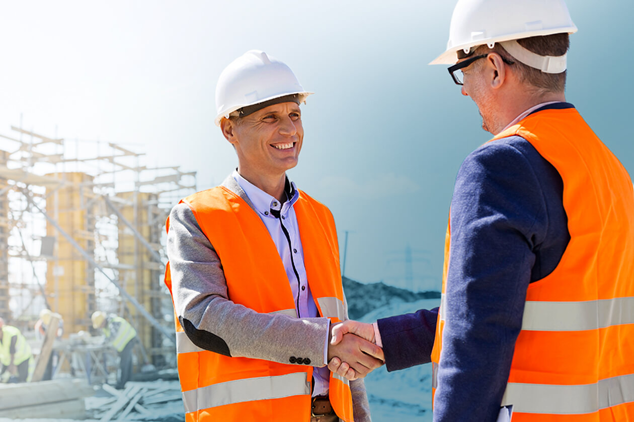 Two workers in hi-vis shaking hands on a construction site